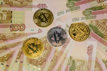Gold and silver bitcoins on Russian banknotes with a face value of one hundred rubles.