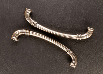 Two metal drawer handles on slate stone, furniture accessories, macro, top view.