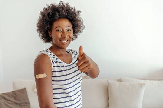 Female get covid-19 immunization at home. Health care and medical procedure. Smiling millennial beautiful African American lady showing arm with band aid after vaccination.