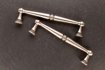 Two metal drawer handles on slate stone, furniture accessories, macro, top view.