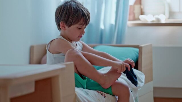 Kid Starts The Day, Getting Ready And Putting Clothes - Little Boy Puts On His Socks Sitting On The Bed, Stands Up And Shows Off His Style