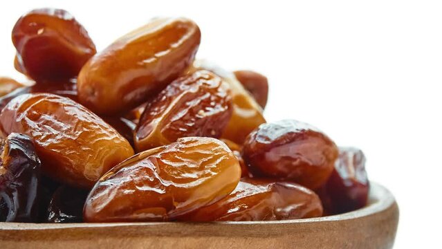 Circular motion Sweet dates in wooden bowl isolated on white background.