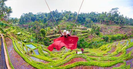 Beautiful young blond girl swing green rice terrace fields of Jatiluwih in the background  - Ubud,  Bali island,  Indonesia