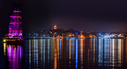Galata Tower, Galata Bridge, Karakoy district and Golden Horn with pirate ship at night, istanbul - Turkey