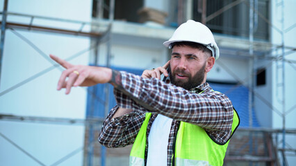 Senior architect or civil engineer talking to phone pointing finger to inspection and control at...