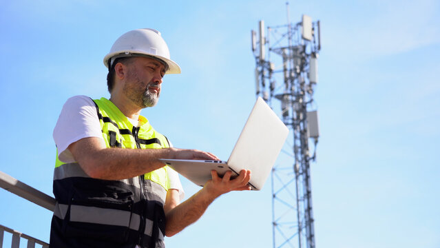 Engineer using laptop computer testing the communications tower