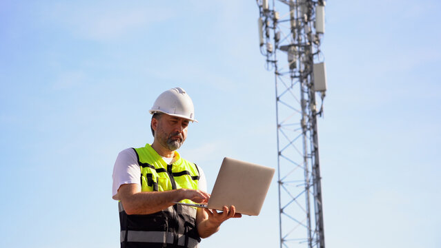 Engineer using laptop computer testing the communications tower
