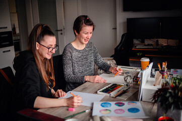 Fototapeta premium A heartwarming scene of two friends laughing and enjoying their artistic hobbies together at a cluttered and lively workspace
