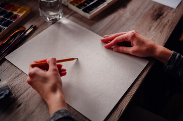 Close-up of hands holding a pencil poised to start a drawing, highlighting the potential of a blank...