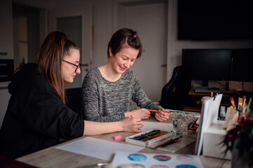 Fototapeta premium In a cozy, cluttered workspace, two women share a light-hearted moment over their art projects, surrounded by creative tools