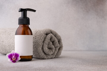 A minimalist spa setup featuring a brown pump bottle with a blank label, accompanied by a delicate...