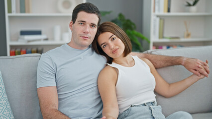 Fototapeta premium Beautiful couple sitting on sofa hugging each other at home
