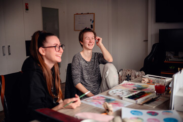 Two friends share a contemplative pause during an art-making session, exchanging ideas and enjoying...