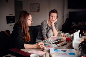 Fototapeta premium Two friends share a contemplative pause during an art-making session, exchanging ideas and enjoying the creative process together