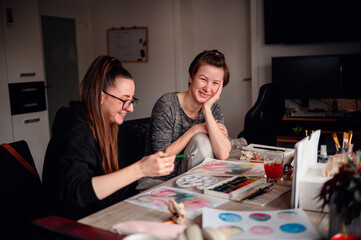 Fototapeta premium Two friends share a contemplative pause during an art-making session, exchanging ideas and enjoying the creative process together