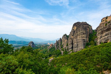 Fototapeta na wymiar Monastery Meteora Greece. Stunning summer panoramic landscape. View at mountains and green forest against epic blue sky with clouds. UNESCO heritage list object.