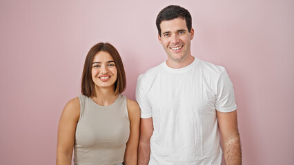 Beautiful couple smiling confident standing together over isolated pink background