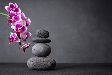Serene stack of smooth grey stones balanced in a zen-like arrangement and pink orchid flowers