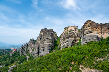 Fototapeta na wymiar Monastery Meteora Greece. Stunning summer panoramic landscape. View at mountains and green forest against epic blue sky with clouds. UNESCO heritage list object.