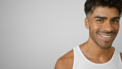 Handsome latino man with beard smiling in white tanktop against isolated white background