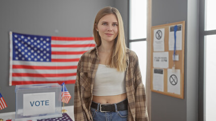 A young blonde woman stands confidently in a usa voting center adorned with flags and informational...