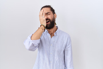 Hispanic man with beard wearing casual shirt yawning tired covering half face, eye and mouth with...