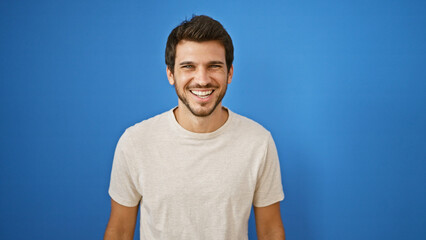 Handsome young hispanic man smiling against a blue background outdoors