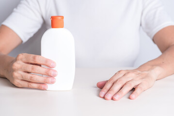 right hand holding mosquito repellent container, and left hand biting mosquito