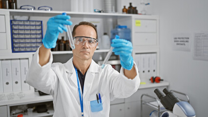 Hispanic middle age man, a serious scientist engrossed in his experiment, securely handles test...
