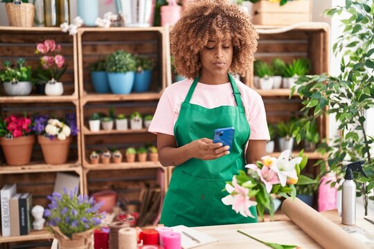 African american woman florist make photo to flowers by smartphone at flower shop