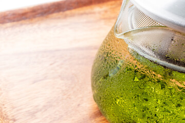 汗をかいたガラスのポットに入った冷たい水出し緑茶