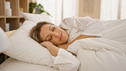 Fototapeta na wymiar Young blonde woman lying on bed sleeping at bedroom