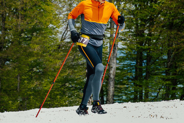male athlete with trekking poles going uphill in snow during race