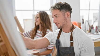 A man and a woman focused on painting in a bright, artistic studio, embodying creativity and collaboration.