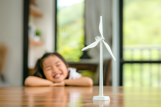 Wind turbine model on the table with cute little asian girl in the background