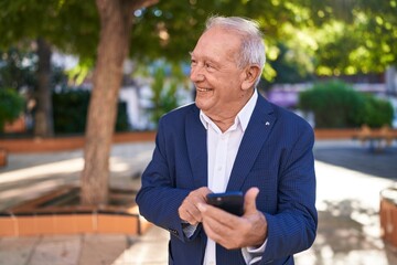 Fototapeta premium Middle age grey-haired man smiling confident using smartphone at park