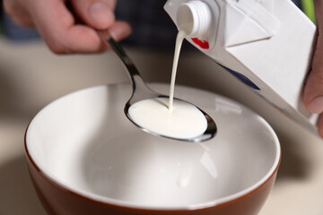 Pouring whipping cream into spoon from UHT carton. Cooking Salted Caramel Chocolate Cold Cake Series.