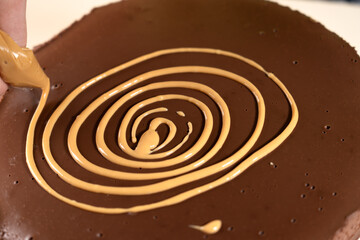 Pipe spiral from caramel sauce on top of cake with pastry bag. Making Salted Caramel Chocolate Cold Cake Series.
