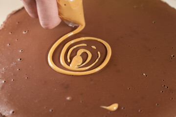 Pipe spiral from caramel sauce on top of cake with pastry bag. Making Salted Caramel Chocolate Cold Cake Series.