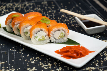 Sushi roll (Philadelphia) with salmon, smoked eel, avocado, cream cheese on black background. Sushi menu. Japanese food.