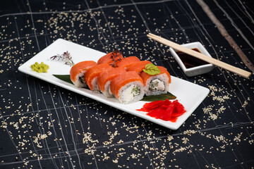 Sushi roll (Philadelphia) with salmon, smoked eel, avocado, cream cheese on black background. Sushi menu. Japanese food.