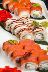 Bright and colorful sushi set with different fish and seafood ingredients on stone serving board on dark background