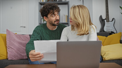 A couple reviewing documents in a cozy living room with a laptop and decorative pillows.