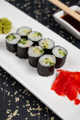 Top view on classic tasty vegetarian kappa maki sushi rolls with fresh cucumbers and rice wrapped in nori on dark background