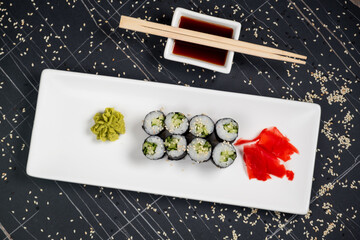 Top view on classic tasty vegetarian kappa maki sushi rolls with fresh cucumbers and rice wrapped in nori on dark background