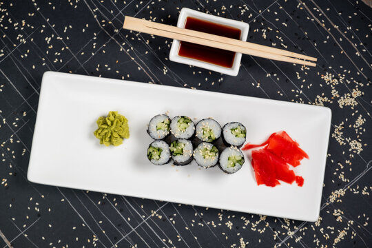 Top view on classic tasty vegetarian kappa maki sushi rolls with fresh cucumbers and rice wrapped in nori on dark background