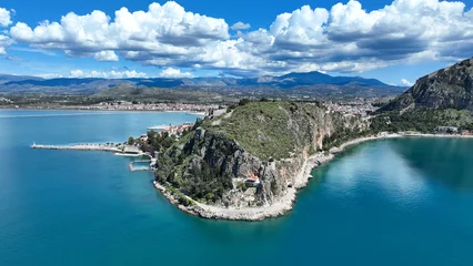 Selbstklebende Fototapeten Aerial drone photo of iconic Acronafplia fortress overlooking old city of Nafplio below famous castle of Palamidi as seen in a spring morning with beautiful clouds and deep blue sky, Argolida, Greece © aerial-drone