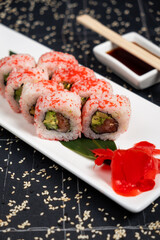 A set of fresh sushi rolls with salmon, avocado and black sesame seeds served on a plate. Japanese sushi uramaki or California roll