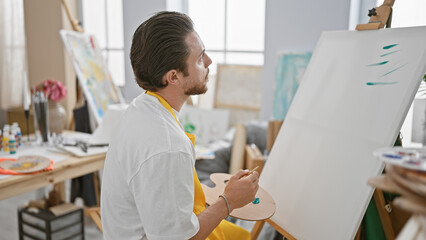 Young hispanic man artist drawing concentrated at art studio