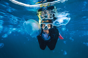 A person is swimming in the ocean with a jellyfish in their hand